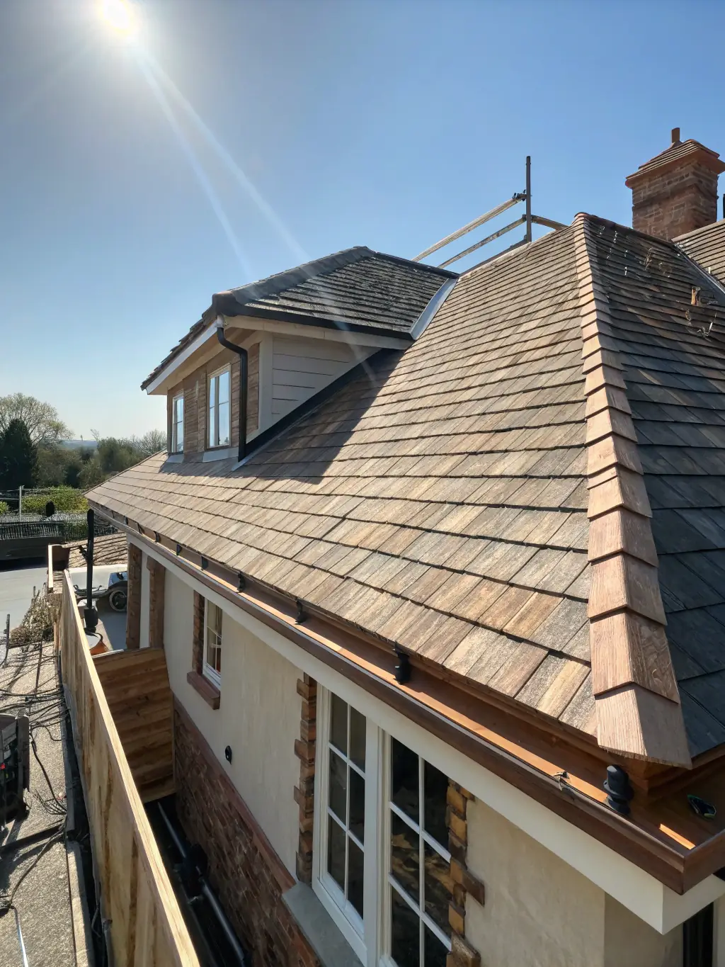 A high-angle, medium shot of a newly installed asphalt shingle roof on a residential home, showcasing clean lines and professional installation. The image should convey durability and quality.